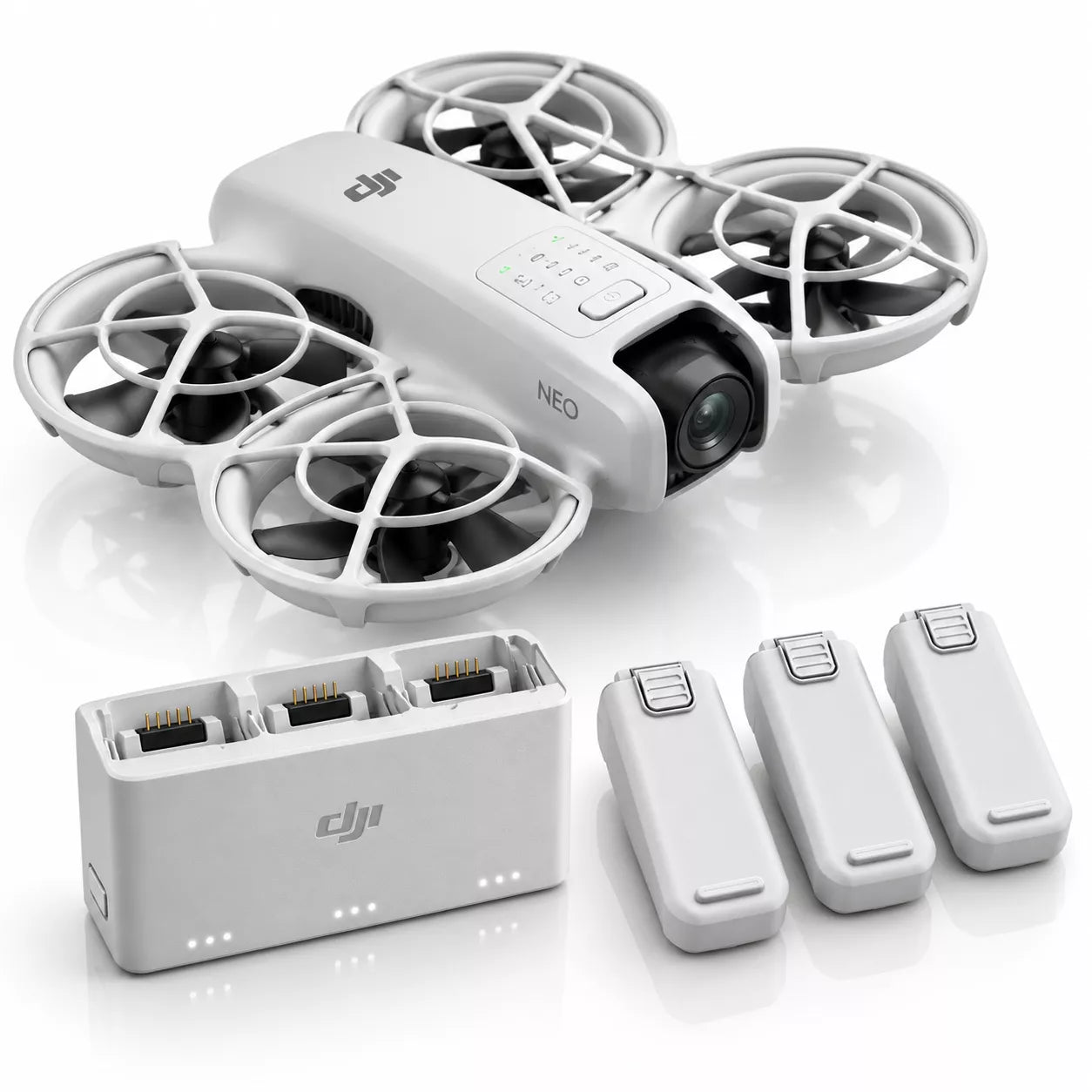 DJI Neo quadcopter drone in white with four protective propellers, shown with a matching white charging dock and four remote controllers on a clean white background.